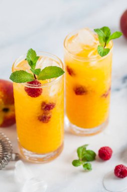 Şeftali suyu ve ahududu mermer bir tablo bir shaker ve aksesuarları bar uzun bardaklarda taze nane ile iki serinletici içecekler.