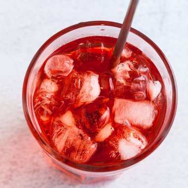 Kırmızı içecek bir cam pipet ile buz küpleri ile. yakın çekim vurdu