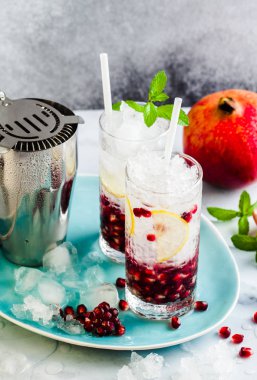 Alkollü içki mojito bir beyaz taş masa ve aksesuarları bar ve nane ile gri arka plan üzerinde limon ve nar tohumları ile yenileme