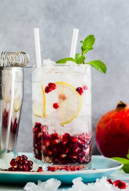 Alkollü içki mojito bir beyaz taş masa ve aksesuarları bar ve nane ile gri arka plan üzerinde limon ve nar tohumları ile yenileme