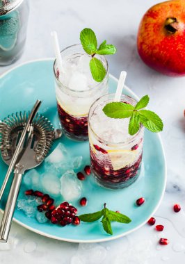 limon ve nar tohumları bir beyaz taş tablo ile alkollü içki ve nane ve bar aksesuarları ile gri arka plan yenileme
