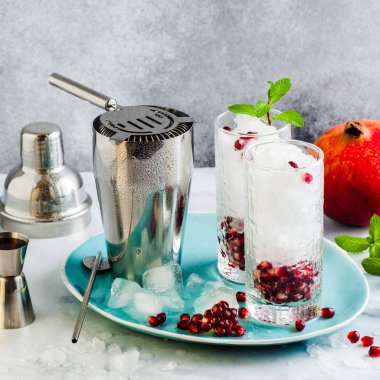 limon ve nar tohumları bir beyaz taş tablo ile alkollü içki ve nane ve bar aksesuarları ile gri arka plan yenileme