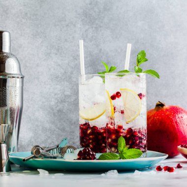 limon ve nar tohumları bir beyaz taş tablo ile alkollü içki ve nane ve bar aksesuarları ile gri arka plan yenileme