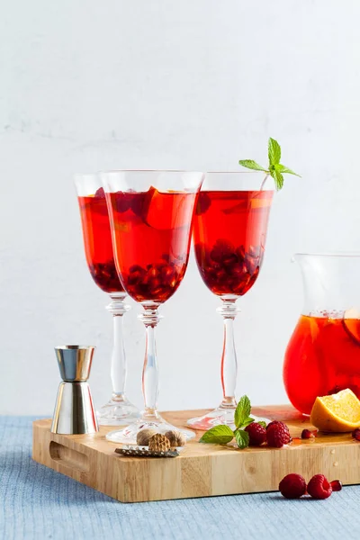 fresh summer red sangria from ripe fruits and berries, as well as wine on the table in glasses and a decanter. spices and mint leaves