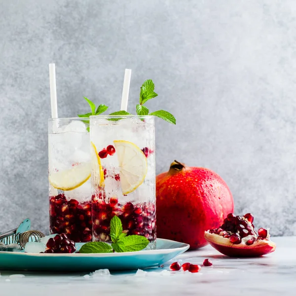 limon ve nar tohumları bir beyaz taş tablo ile alkollü içki ve nane ve bar aksesuarları ile gri arka plan yenileme