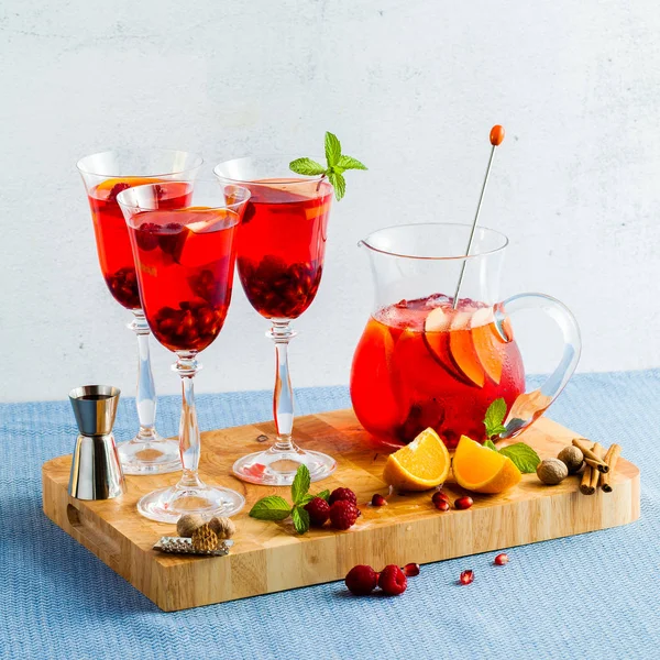 fresh summer red sangria from ripe fruits and berries, as well as wine on the table in glasses and a decanter. spices and mint leaves