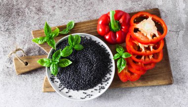 kırmızı, Olgun, dolmalık biber bir kesme tahtası ve taze fesleğen yaprakları kesti. Siyah mercimek. Arka plan gri taş yemek pişirme 