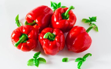Grup kırmızı olgun organik biber ve taze fesleğen yaprakları üzerinde beyaz izole