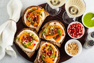 lezzetli bruschettes Humus, pişmiş kabak ve roka pesto masanın üzerinde. beyaz şarapla Vegan sağlıklı yemekler servis