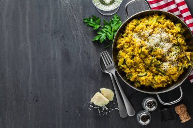 İtalyan yemek sarı Risotto milanese safran, kabak ve Parmesan peyniri bir bardak beyaz şarap bir siyah arduvaz masada. Kuzey İtalya mutfak. kopya alanı