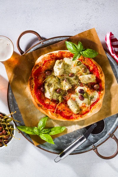 Classic Italian Pizza Margherita with artichokes, olives and capers on a table with beer and a knife. Banner for restaurants, advertising.