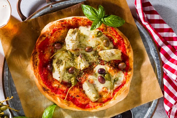 Classic Italian Pizza Margherita with artichokes, olives and capers on a table with beer and a knife. Banner for restaurants, advertising.