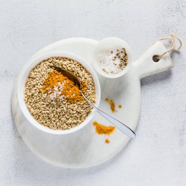 tam tahıllı pirinç bir kase beyaz mermer boyutunda bir tahta üzerinde zerdeçal ile. bir vegan sağlıklı mutfak malzemeleri