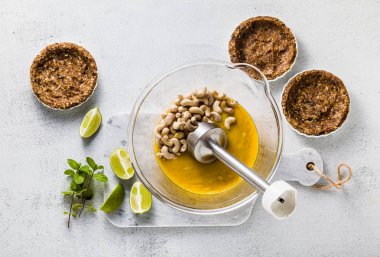 Mini turta fındık ve tarihler için vegan paleo kaju fıstığı ve mango püresi krem hazırlanması. sağlıklı alternatif çiğ gıda ile el blender'ı