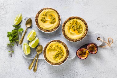 Vegan ham mini-turta fındık ve tarihleri kaju-mango kremalı limon suyu ve tutku meyve tohumları ile saf. beyaz mermer zemin üzerinde sağlıklı alternatif gıda