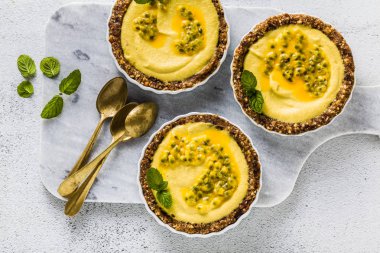 Vegan ham mini-turta fındık ve tarihleri kaju-mango kremalı limon suyu ve tutku meyve tohumları ile saf. beyaz mermer zemin üzerinde sağlıklı alternatif gıda