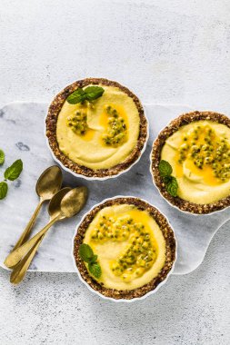 Vegan ham mini-turta fındık ve tarihleri kaju-mango kremalı limon suyu ve tutku meyve tohumları ile saf. beyaz mermer zemin üzerinde sağlıklı alternatif gıda