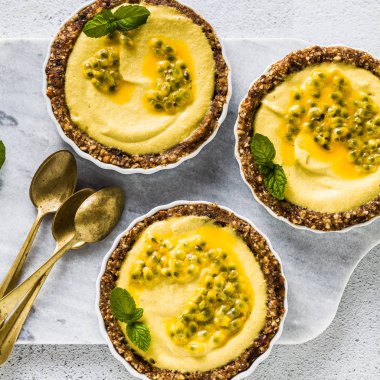 Vegan ham mini-turta fındık ve tarihleri kaju-mango kremalı limon suyu ve tutku meyve tohumları ile saf. beyaz mermer zemin üzerinde sağlıklı alternatif gıda