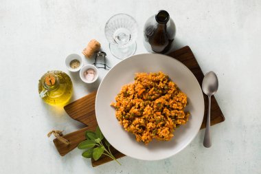 İtalyan risotto ile domates sosu ve yeşil bezelye, ahşap kesme tahtası ve bir şişe köpüklü şarap tabakta servis. klasik Akdeniz mutfağı. Tüm aile için sağlıklı vegan yemek