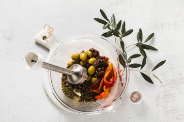 Doğrama Kurulu bir mermer üzerinde mercimek salatası yemek pişirmek için malzemeler. zeytin ağacı ve el blender Şubesi