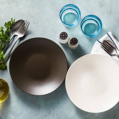 Tablo ayarı. iki boş tabak, baharat, çatal bıçak takımı ve zeytin yağı. metin yazmak için bir yer. kopya alanı. kolaj şablonu