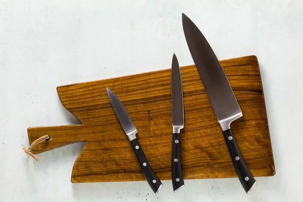 a set of knives on a wooden cutting board.