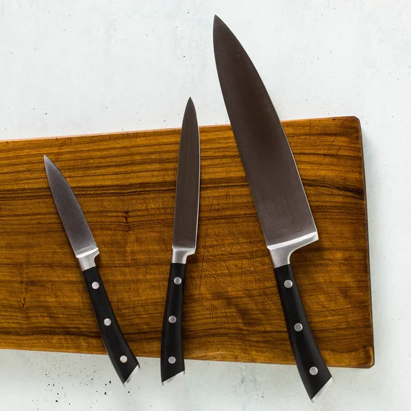 a set of knives on a wooden cutting board.