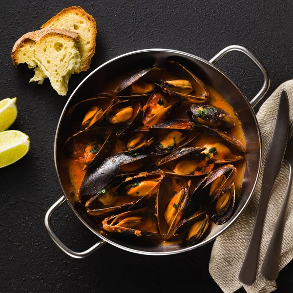 freshly cooked mussels in a frying pan in tomato sauce. pepata di cozze or mussels marinara. classic dish of mediterranean italian cuisine. on black background