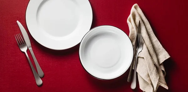 banner of empty dining table set for two. two aluminum plates on a raspberry table with napkins and cutlery. copy space