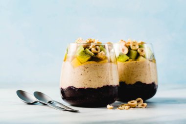 Vegan muz tatlı yeşil buğday, chia tohum ve bir bardak taze meyve, fındık ve bal ile yaban mersini reçeli ile quinoa, katmanlı. sağlıklı sabah yemek kahvaltı.