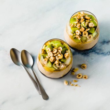 Vegan muz tatlı yeşil buğday, chia tohum ve bir bardak taze meyve, fındık ve bal ile yaban mersini reçeli ile quinoa, katmanlı. sağlıklı sabah yemek kahvaltı.