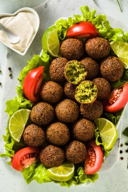 Vegan falafel doğranmış domates ve limon dilimleri ile bir tabloda kaju peynir soslu. Tüm aile veya parti için sağlıklı gıda