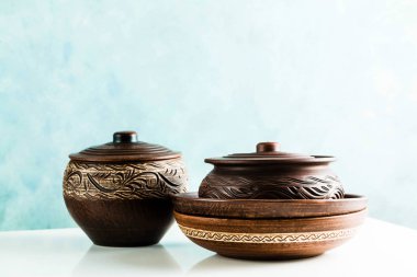 Tencere ve plakaları kil beyaz bir tablo ve mavi bir arka plan üzerinde. kil çömlek mutfak eşyaları elle yapılan. Kırmızı kil sofra