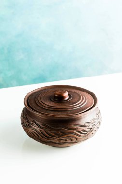 Tencere ve plakaları kil beyaz bir tablo ve mavi bir arka plan üzerinde. kil çömlek mutfak eşyaları elle yapılan. Kırmızı kil sofra