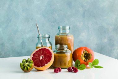 farklı gözlük ile taze greyfurt, kivi, Trabzon hurması ve ahududu smoothies yaptı. beyaz masa ve mavi arka plan. sağlıklı gıda. sabah kahvaltı