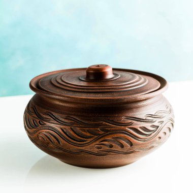 Tencere ve plakaları kil beyaz bir tablo ve mavi bir arka plan üzerinde. kil çömlek mutfak eşyaları elle yapılan. Kırmızı kil sofra