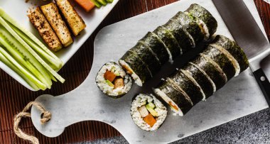 afiş balık tabakları masaya vegan hazır suşi. Kızarmış tofu, salatalık, haşlanmış havuç ve taze avokado ile alır. sağlıklı vegan gıda