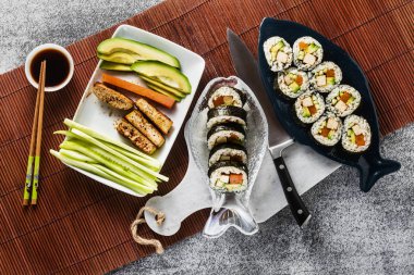 Vegan hazır suşi balık tabakları masaya. Kızarmış tofu, salatalık, haşlanmış havuç ve taze avokado ile alır. sağlıklı vegan gıda