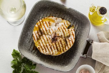 Kızarmış kılıç balığı biftek ızgara Pan zeytinyağı ve baharatlar ile. beyaz şarap kadehi