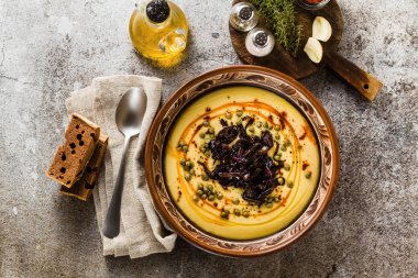 Otantik Yunan Fava tarifi, karamelize soğan, kırmızı biber ve kapari ile Orta Doğu sarı mercimek çorbası. kil tencere taş masanın üzerine Vegan sağlıklı gıda