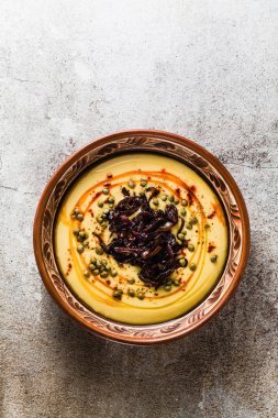 Otantik Yunan Fava tarifi, karamelize soğan, kırmızı biber ve kapari ile Orta Doğu sarı mercimek çorbası. kil tencere taş masanın üzerine Vegan sağlıklı gıda