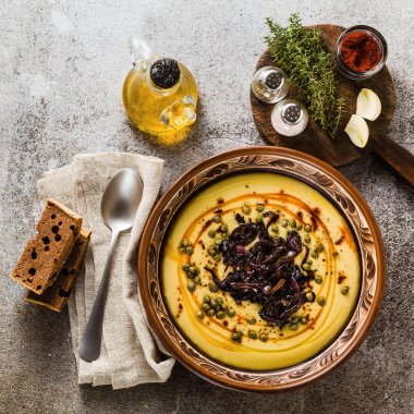 Otantik Yunan Fava tarifi, karamelize soğan, kırmızı biber ve kapari ile Orta Doğu sarı mercimek çorbası. kil tencere taş masanın üzerine Vegan sağlıklı gıda