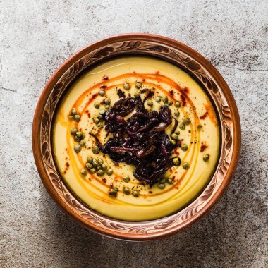 Otantik Yunan Fava tarifi, karamelize soğan, kırmızı biber ve kapari ile Orta Doğu sarı mercimek çorbası. kil tencere taş masanın üzerine Vegan sağlıklı gıda