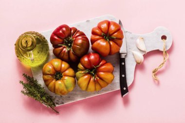 bir kesme tahtası üzerinde Brandywine domates. yemek yaz salata taze zeytinyağı, kekik. gül bir arka plan üzerinde