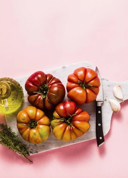 bir kesme tahtası üzerinde Brandywine domates. yemek yaz salata taze zeytinyağı, kekik. gül bir arka plan üzerinde