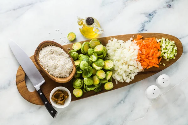 在木制切菜板和大理石桌子上使用芽甘蓝的利索托原料 厨师的刀 橄榄油和香料 健康的素食主义者食品 — 图库照片