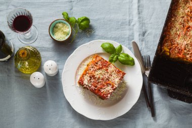 Mercimek ve bir fırın tepsisine bir mavi keten masa örtüsü ile bir tabloda yeşil bezelye ile vejeteryan lazanya. Bütün aile, parti ya da restoran ve kırmızı şarap gözlük için sağlıklı İtalyan mutfağı