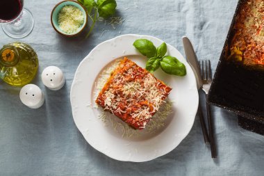 Mercimek ve bir fırın tepsisine bir mavi keten masa örtüsü ile bir tabloda yeşil bezelye ile vejeteryan lazanya. Bütün aile, parti ya da restoran ve kırmızı şarap gözlük için sağlıklı İtalyan mutfağı