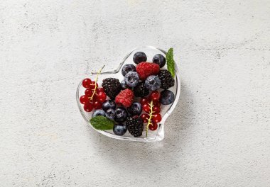 Bir taş beyaz bir cam kalp şeklinde kase taze olgun çilek