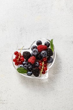 Bir taş beyaz bir cam kalp şeklinde kase taze olgun çilek